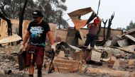 Men remove debris from houses destroyed by a forest fire in the hills of Tome, Concepcion province, Biobio region, Chile on February 4, 2023.  (Photo by JAVIER TORRES / AFP)