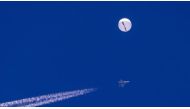A large balloon drifts above the Atlantic Ocean, just off the coast of South Carolina, with a fighter jet and its contrail seen below it on February 4, 2023. (AP/Chad Fish)