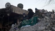 Relatives sit on top of rubble of collapsed buildings, as rescue teams continue to search victims and survivors, in Kahramanmaras on February 12, 2023. (Photo by Ozan Kose / AFP)