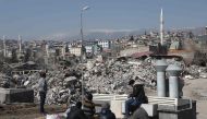 Men look on at the site of collapsed buildings in Kahramanmaras, southeastern Turkey, on February 18, 2023.  (Photo by Zein Al RIFAI / AFP)