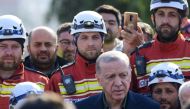 Turkish President Recep Tayyip Erdogan stands with rescue workers as he visits the hard-hit southeastern province of Hatay on February 20, 2023. (Photo by Yasin Akgul / AFP)