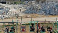 An aerial view shows children playing by the rubble of destroyed buildings in the village of Azmarin in Syria's rebel-held northwestern Idlib province at the border with Turkey on February 18, 2023 following a 7.8-magnitude earthquake. (Photo by OMAR HAJ KADOUR / AFP)