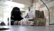 File Photo: An employee takes bundles of Yemeni Riyal. (REUTERS/Khaled Abdullah)