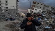 A man speaks on the phone in front of collapsed buildings, a day after a 6.4-magnitude earthquake struck the region, in the coastal city of Samandag, in Turkiye, on February 21, 2023. (Photo by BULENT KILIC / AFP)