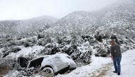 A good samaritan checks on a vehicle which skidded off the snowy roadway into a small pond in Los Angeles County, in the Sierra Pelona Mountains, on February 25, 2023 near Green Valley, California. Mario Tama/Getty Images/AFP 
