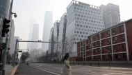 A woman crosses a street at central business district in Beijing on March 5, 2023 (Photo by Jade Gao / AFP)