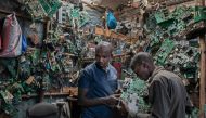 David Gathu (R), 30, and Moses Kiuna (L), 29, both self-taught innovators, rumage through salvaged electrical components at an open-air market stall that specialises in trade in electrical waste in Nairobi on January 31, 2023.  Photos by Tony KARUMBA / AFP