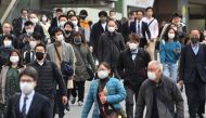 Commuters walk on a street in Shinjuku district of Tokyo on March 13, 2023 on the first day of reduced mask requirements. Photo by Kazuhiro NOGI / AFP