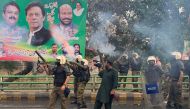 Riot police fire teargas shells to push back supporters of former prime minister Imran Khan gathered outside Khan's house to prevent officers from arresting him, in Lahore on March 14, 2023. (Photo by Arif Ali / AFP)