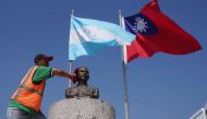 (FILES) In this file photo taken on March 15, 2023, a municipal worker cleans the bust of Sun Yat-sen, founder and first provisional president of the Republic of China, beneath the flags of Honduras (L) and Taiwan at a square in Tegucigalpa. (Photo by Stringer / AFP)