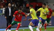 :Morocco's midfielder Hakim Ziyech (L) is marked by Brazil's defender Alex Telles (C) during a friendly football match between Morocco and Brazil at the Ibn Batouta Stadium in Tangier on March 26, 2023. Photo by Fadel Senna / AFP
