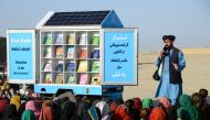 In this photograph taken on May 17, 2022, Matiullah Wesa, head of PenPath and advocate for girls' education in Afghanistan, speaks to children during a class next to his mobile library in the Spin Boldak district of Kandahar Province. (Photo by Sanaullah Seiam / AFP)