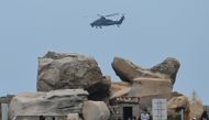A Chinese military helicopter flies past tourists at a viewing point over the Taiwan Strait, on Pingtan island, the closest point to Taiwan, in China's southeast Fujian province on April 7, 2023. (Photo by GREG BAKER / AFP)