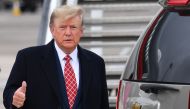 Former US President Donald Trump gestures to members of the media on the tarmac after disembarking 