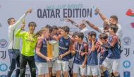 Paris Saint Germain Academy Qatar players and officials celebrate with the GCC Cup trophy.
