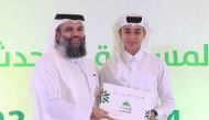 Dr. Sheikh Khalid bin Mohammed bin Ghanem Al Thani, Director of General Department of Endowments honouring a winner of Al Muhaddis Al Saghir competition during a ceremony.