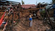 A Rohingya woman stands in her destroyed house at Basara refugee camp in Sittwe on May 16, 2023. (Photo by SAI Aung MAIN / AFP)