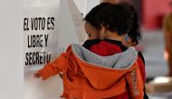 A woman carrying a child casts her ballot at a polling station in Texcoco, Mexico, on June 4, 2023, during gubernatorial elections in the State of Mexico. (Photo by CLAUDIO CRUZ / AFP)