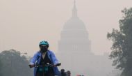 A cyclist rides under a blanket of haze partially obscuring the US Capitol in Washington, DC, on June 8, 2023. (Photo by Mandel Ngan / AFP)
