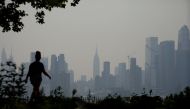 The Manhattan skyline is seen across the Hudson river past a pedestrian walking along the waterfront in West New York. (Photo by Leonardo Munoz / AFP)
