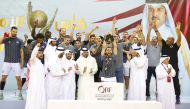 QOC President H E Sheikh Joaan bin Hamad Al Thani applauds as Al Sadd's players and officials celebrate after receiving the prestigious Amir Cup trophy following their win over Al Ahli in the final at Al Gharafa Sports Club yesterday.   