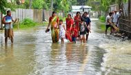 People wade through a flooded road in Ghograpar village of Nalbari district, in India's Assam state. (Photo by Biju BORO / AFP)