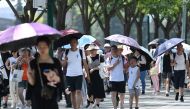 People shelter from the sun under umbrellas after visiting the Forbidden City during a heatwave in Beijing on June 24, 2023. Photo by GREG BAKER / AFP