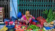 A woman eats a snack while waiting for costumers at a market in Banda Aceh on July 3, 2023. (Photo by CHAIDEER MAHYUDDIN / AFP)
