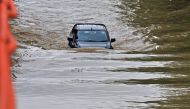 A commuter drives his car through a flooded road after heavy monsoon rains in Gurgaon on July 9, 2023. (Photo by Vinay Gupta / AFP)
