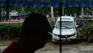 A man walks past a damaged car after heavy rains in Mentougou district in Beijing on August 1, 2023. Photo by Pedro PARDO / AFP