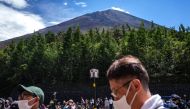 This picture taken on August 14, 2022 shows tourists gathered at the bus terminals of Fuji Subaru Line 5th Station with the background of Mount Fuji, Japan's highest mountain at 3,776 meters (12,388 feet). Photo by Philip FONG / AFP