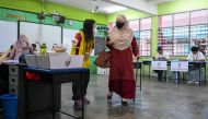 A woman (centre R) carries her ballot paper before casting her vote during the state election at a polling station in Selayang in Malaysia's Selangor state on August 12, 2023. (Photo by Mohd Rasfan / AFP)