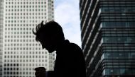 A pedestrian carries a coffee cup in London's central business district of Canary Wharf, on August 14, 2023. Photo by HENRY NICHOLLS / AFP