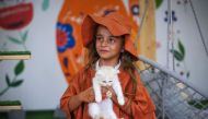 A girl holds a feline at the newly inaugurated Cat Cafe in Gaza City on August 17, 2023. (Photo by Mohammed Abed / AFP)