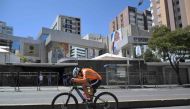 A man rides a bicycle outside the National Electoral Council in Quito, on August 18, 2023. Amid the commotion over the shooting death of a candidate and violence linked to drug trafficking, Ecuador will vote this Sunday in early elections to elect a new president and put an end to an institutional crisis. (Photo by Rodrigo BUENDIA / AFP)
