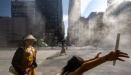 People walk past an overhead water misting system on a hot day in the Ginza district of Tokyo on July 10, 2023.(Photo by Philip Fong / AFP)