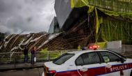 Police drive past bamboo scaffolding that has been brought down by Typhoon Saola at Kowloon Tong in Hong Kong on September 2, 2023. (Photo by Isaac Lawrence / AFP)