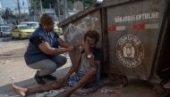 Nurse Assistant Sandra Maria (L) gives a COVID-19 vaccine to a homeless man in the suburbs of Rio de Janeiro, Brazil on July 12, 2023. (Photo by Mauro Pimentel /  AFP)