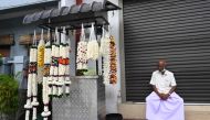 A man sits next to a flowers stall in Colombo on September 14, 2023. (Photo by Farooq Naeem / AFP)