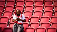 A supporter of Feyenoord checks his smartphone after the Dutch Eredivisie football match between Ajax Amsterdam and Feyenoord was ended following fireworks thrown on the field at the Johan Cruijff Arena in Amsterdam on September 24, 2023. (Photo by Olaf Kraak / ANP / AFP) / Netherlands OUT
