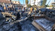 People search through debris outside the site of the Ahli Arab hospital in central Gaza on October 18, 2023 in the aftermath of an overnight blast there. (Photo by Mahmud Hams / AFP)