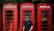 Owner Carl Burge, poses for a portrait in front of traditional red telephone boxes at 