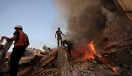 Palestinian rescuers attempt to put out a fire as they stand on the rubble of a collapsed building following a strike by the Israeli military on Khan Yunis in the southern Gaza Strip on November 4, 2023. (Photo by Mahmud Hams / AFP)