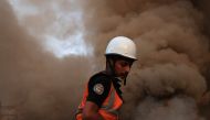 A Palestinian rescuer stands in the dust and smoke rising following a strike by the Israeli military on Khan Yunis in the southern Gaza Strip on November 4, 2023. Photo by MAHMUD HAMS / AFP