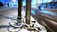 A snow-covered bicycle lies on a sidewalk during a snowfall in Beijing on December 14, 2023. (Photo by GREG BAKER / AFP)
