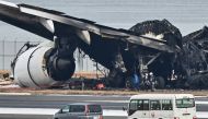 Officials look at the burnt wreckage of a Japan Airlines (JAL) passenger plane on the tarmac at Tokyo International Airport at Haneda in Tokyo on January 3, 2024, the morning after the JAL airliner hit a smaller coast guard plane on the ground. Photo by Richard A. Brooks / AFP
