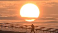 A person crosses a footbridge as the first sunrise of the new year is seen in Seoul on January 1, 2024. (Photo by Jung Yeon-je / AFP)