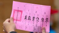 An official of a polling station examines a ballot slip, as vote counting for the presidential election commences, at a high school in New Taipei City on January 13, 2024. (Photo by Sam Yeh / AFP)