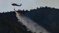 A helicopter from the Colombian Police drops water to put out a forest fire in Bogota on January 24, 2024. (Photo by Luis Acosta / AFP)
 
