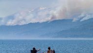 A picture released by Telam news agency shows tourists looking at smoke billowing from a forest fire at Los Alerces National Park in Chubut province, Argentina, on January 28, 2024. Photo by MARTIN LEVICOY / TELAM / AFP